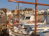 barcos tipicos de los pescadores menorqines atracados en el muelle de la bahia de fornells, realza la belleza del enclave de la costa norte de la isla