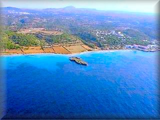 Vista aérea de la urbanización de Santo tomas a la derecha de la panorámica y las playas de Binigaus al final de las tierras de cultivo, el islote es 